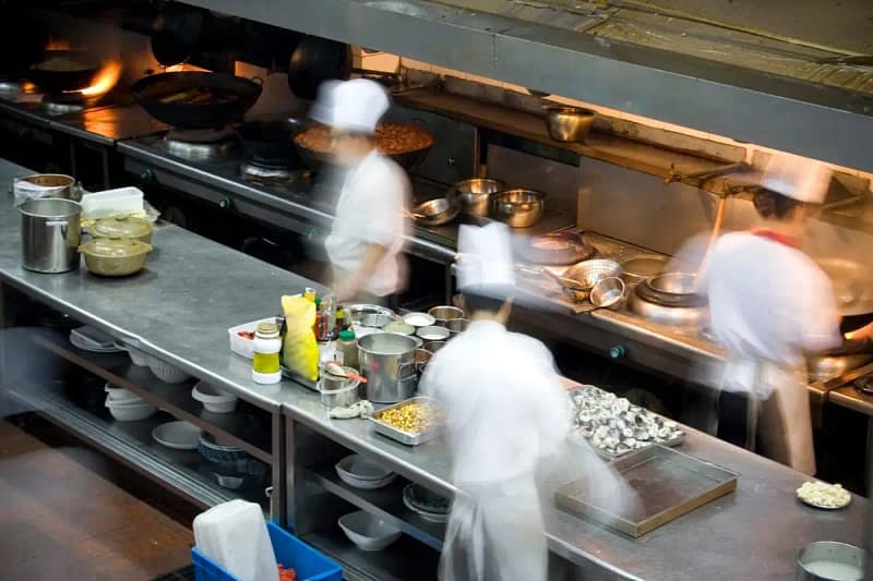 Cozinha de restaurante com chefs em movimento, simbolizando o trabalho em equipe e a eficiência operacional em restaurantes de São Paulo.